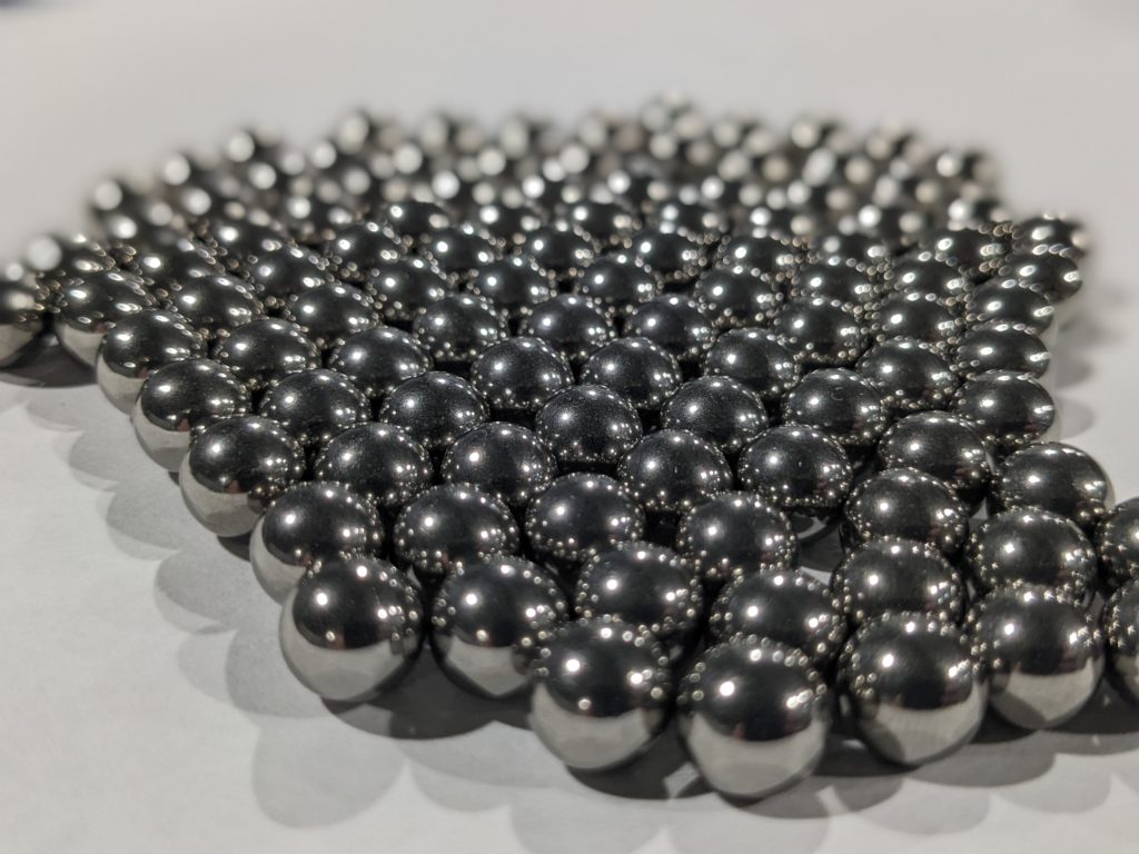 Figure 5 — Reference photograph of tungsten heavy-alloy spheres in a range of sizes (Elmet Technologies — comparable product line to Midwest Tungsten Service's MT-17F WNF). The 3.5″ sphere ordered for this bu…