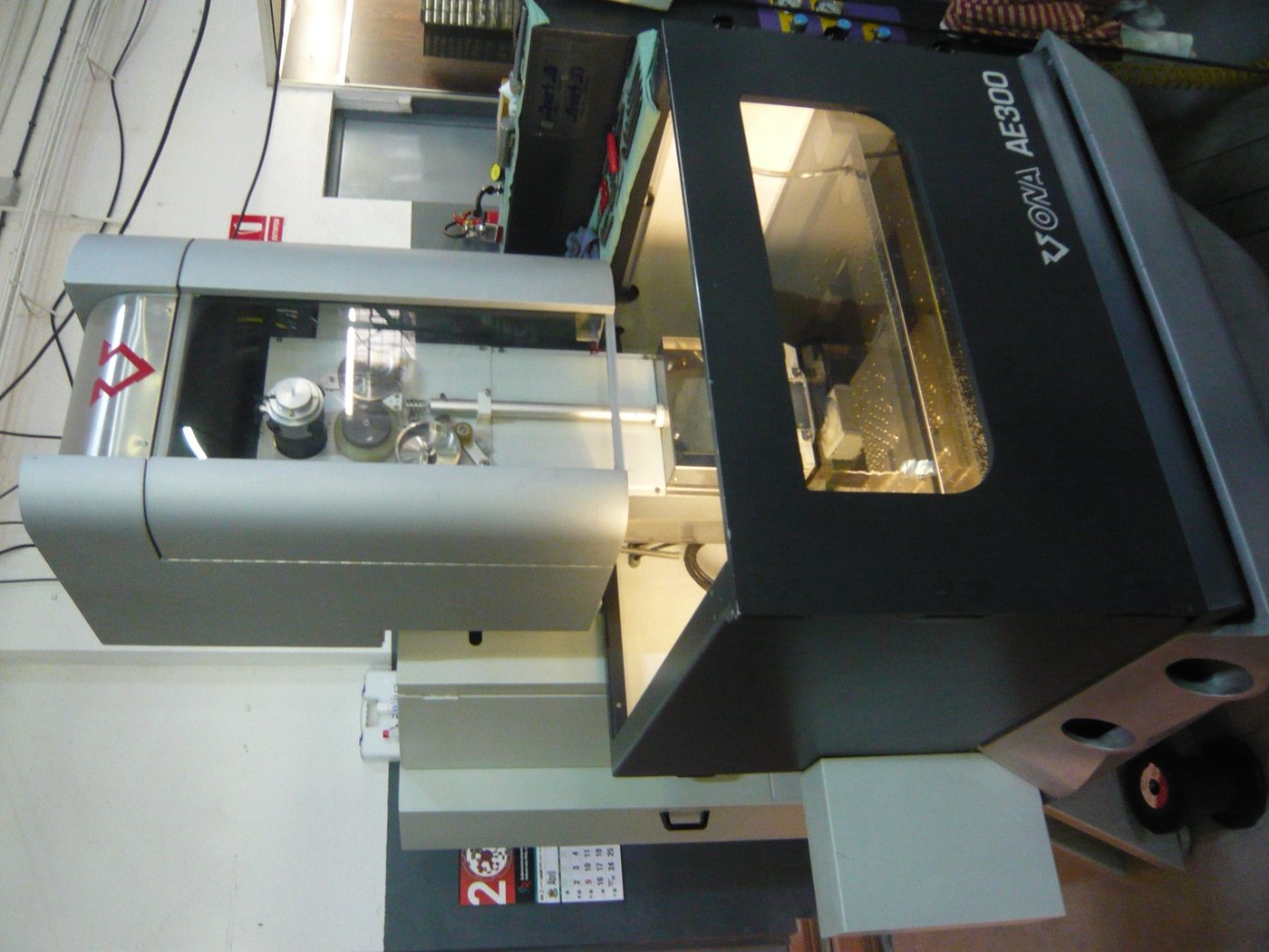 Figure 6 — Reference photograph of an Ona AE300 wire-EDM machine — the class of equipment a local job shop will use to bisect the tungsten sphere on the equator. A 0.010″ brass wire under tension passes throu…